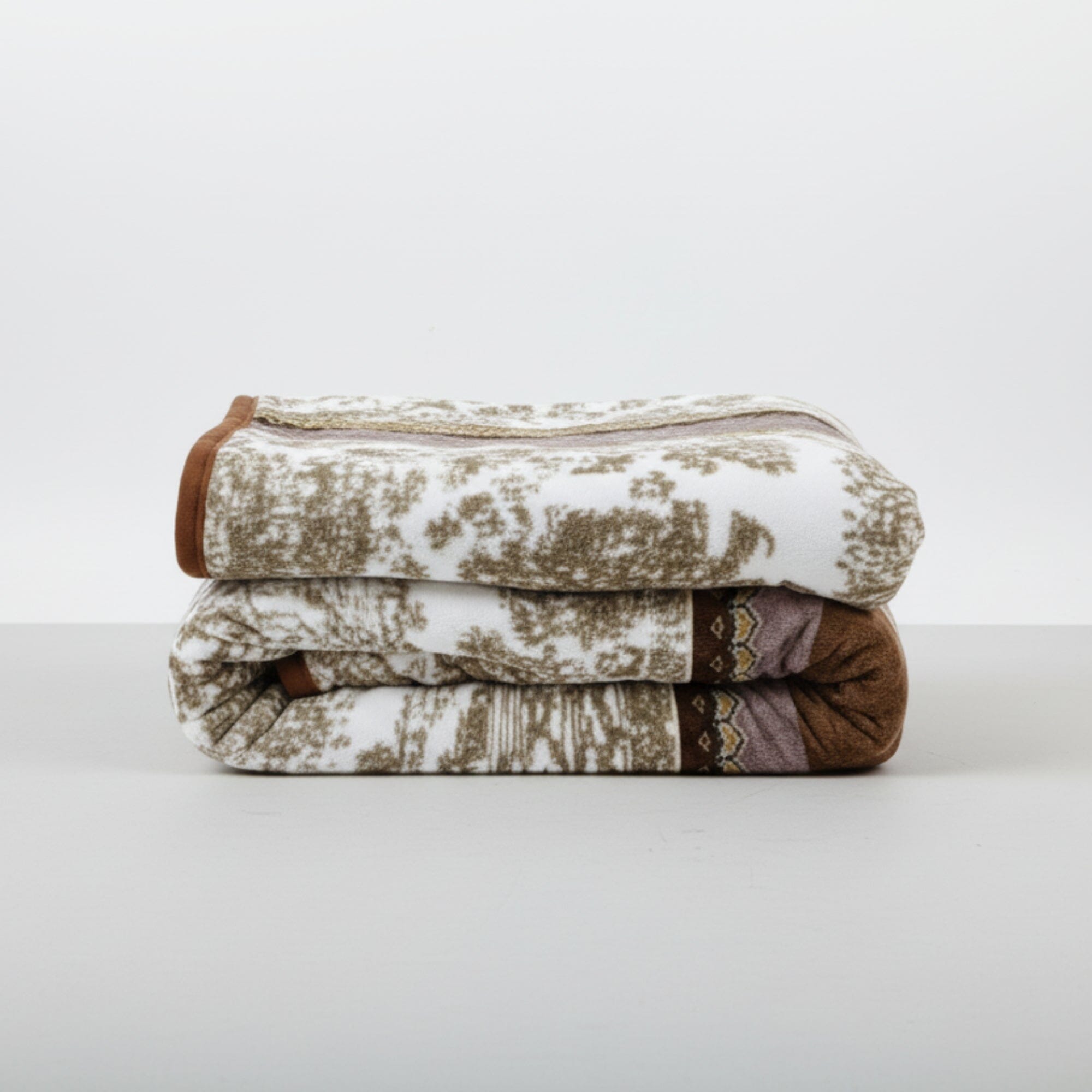 Stack of patterned mink blankets on a white surface with a white background